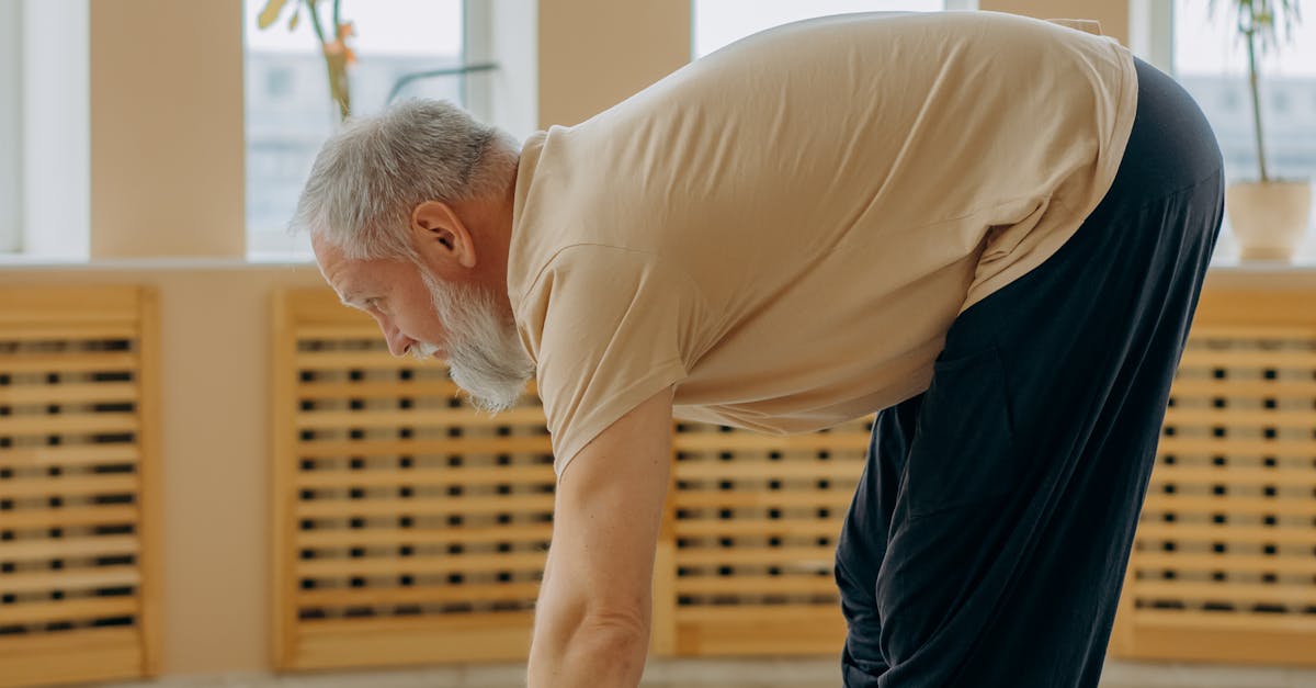Senior man stretching on a yoga mat indoors, promoting healthy and active aging.
